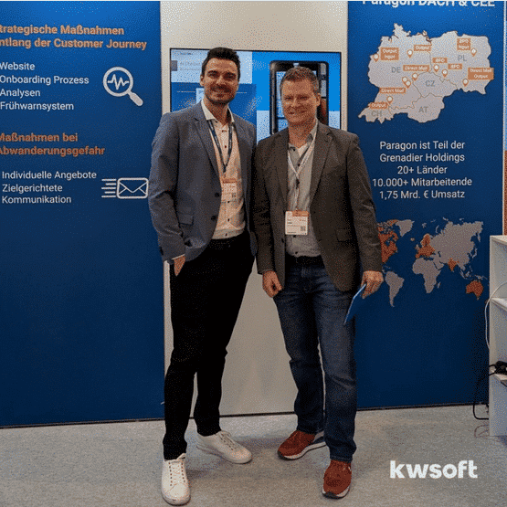 Marco Leven and Philip Moser standing in front of the Paragon Display at the E-world 2025.