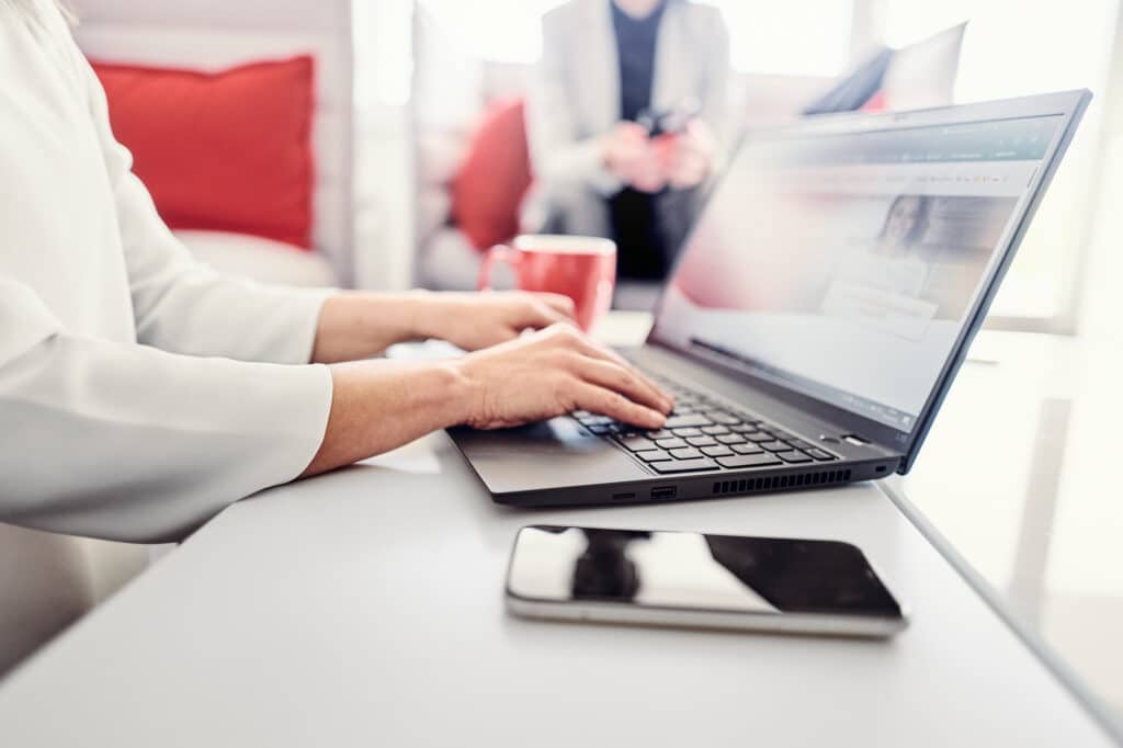 A person is sitting at a laptop and visiting the Kwsoft website.