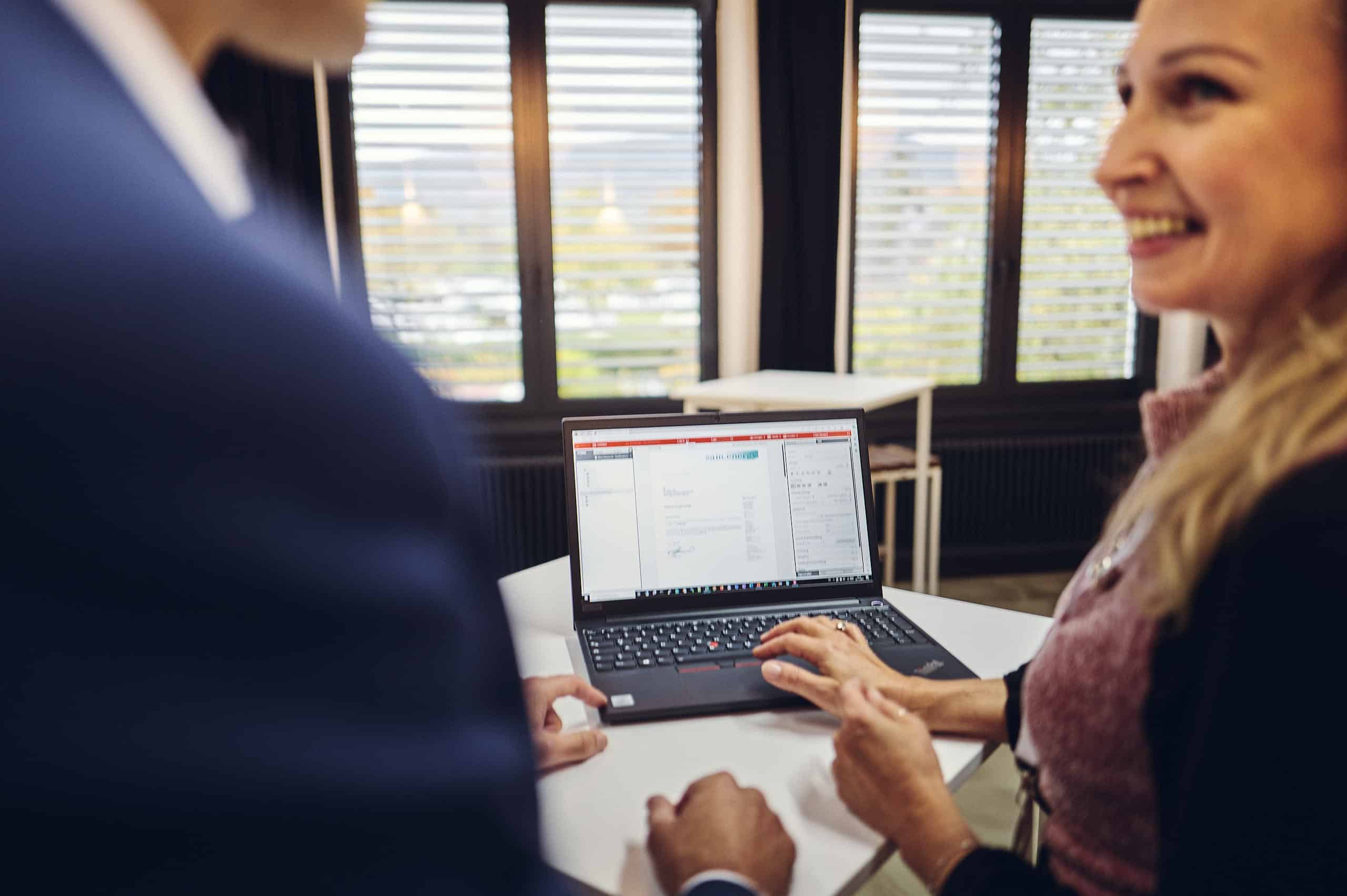 Two people are looking at a laptop and talking about it.